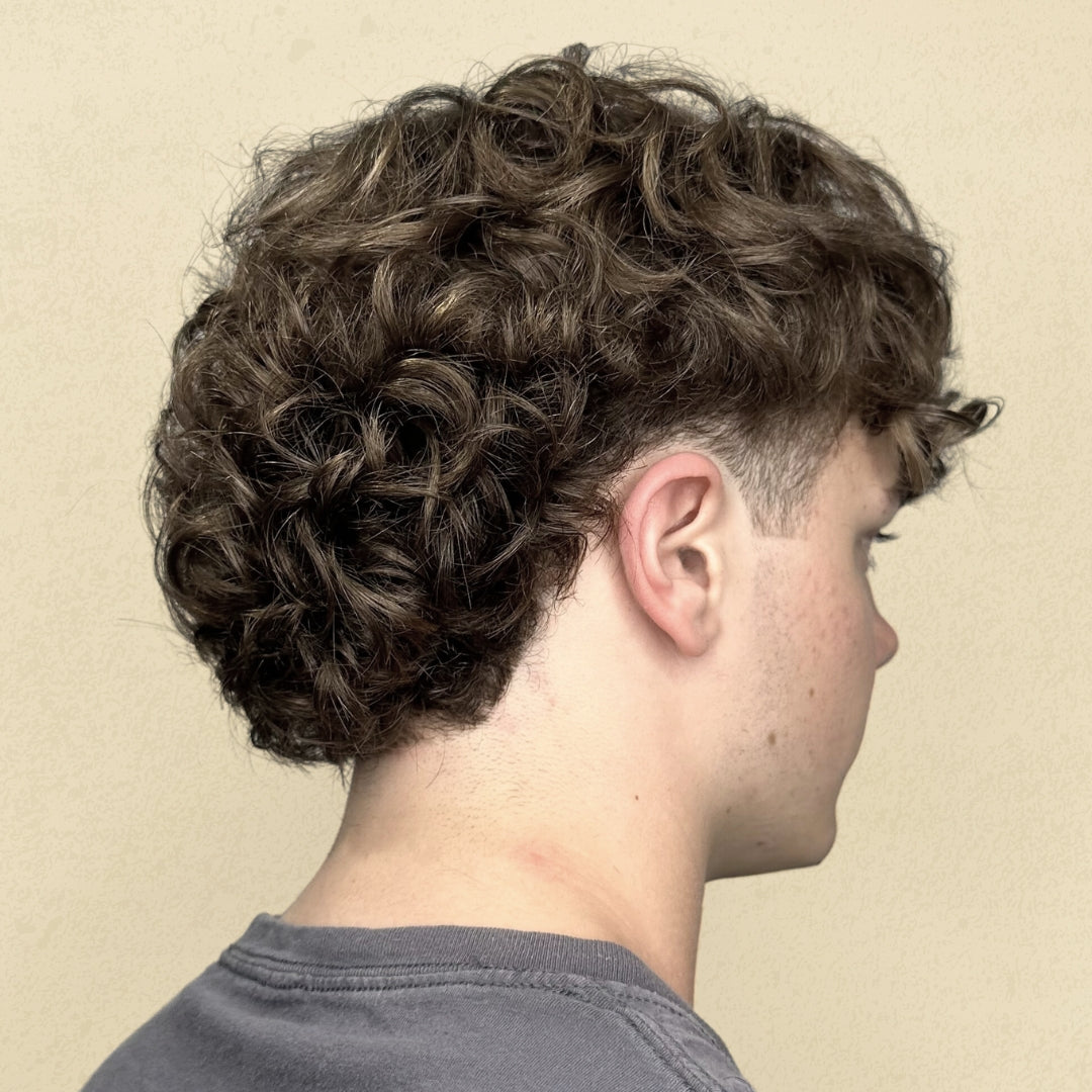 This is an image of a boy with a super curly head of hair showcasing his new, rad, haircut done by a stylist at Ippodaro Natural Salon, in San Antonio, Texas.